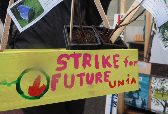 Ein gelb gestrichenes Holzschild mit der Aufschrift «Strike for Future Unia» steht vor Pflanzentöpfen und verweist auf eine Aktion der Gewerkschaft Unia im Rahmen des Klimastreiks.